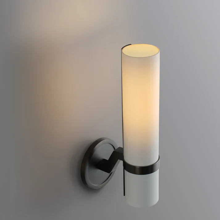 Wall-mounted light fixture with cylindrical glass shade on a gray background